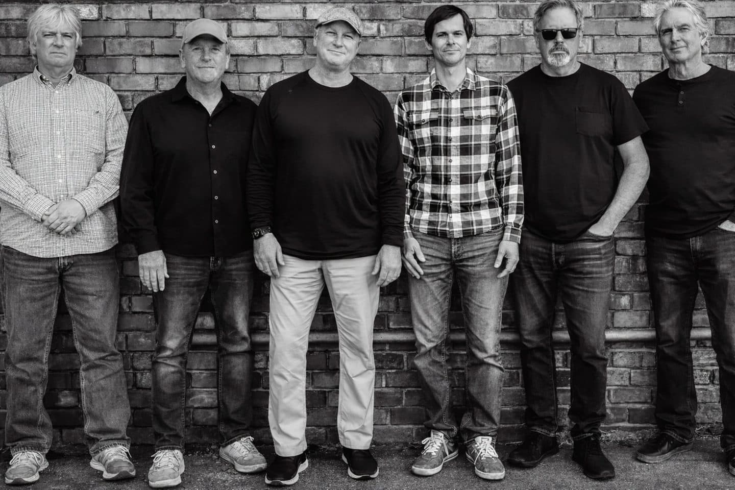 The band standing together in front of a brick wall